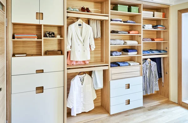Ahşap gardırobun iç detayları. Bardaklar için askılık. Giysileri raflarda asılı ve raflarda katlanmış modern gardırop. Modern mobilya