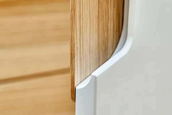 Detail of the wardrobe close-up. Modern wooden wardrobe with flat finger pull wardrobe doors. Oak veneered plywood cabinets with light gray painted cabinet doors. Modern furniture