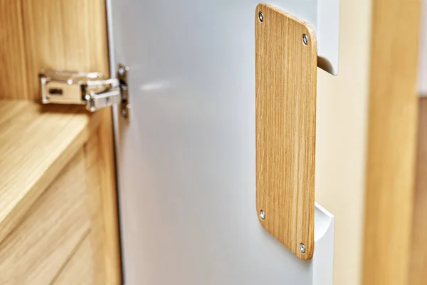 Detail of the wardrobe close-up. Modern wooden wardrobe with flat finger pull wardrobe doors. Oak veneered plywood cabinets with light gray painted cabinet doors. Modern furniture