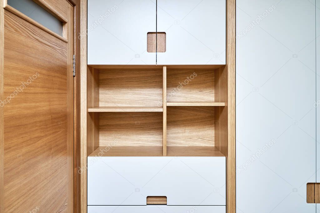 Detail of the wardrobe close-up. Modern wooden wardrobe with flat finger pull wardrobe doors. Oak veneered plywood cabinets with light gray painted cabinet doors. Modern furniture
