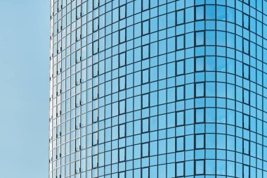 Parlak mavi cam cepheli şık ofis binası güneşli bir günde açık mavi gökyüzüne karşı parlak güneş ışığını yansıtıyor.