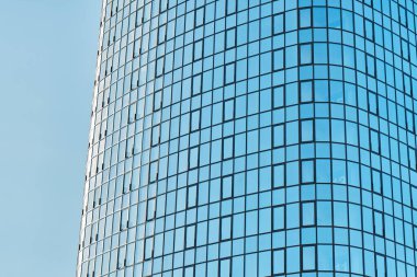 Parlak mavi cam cepheli şık ofis binası güneşli bir günde açık mavi gökyüzüne karşı parlak güneş ışığını yansıtıyor.