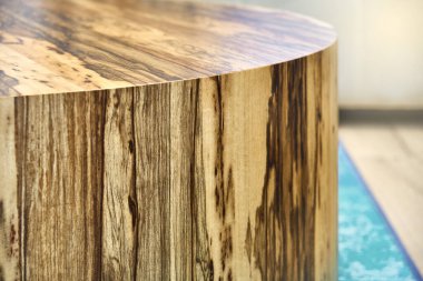 Kontrplaktan yapılmış zarif yuvarlak sehpanın yanı ve oturma odasında duran doğal siyah Ofram kaplaması.