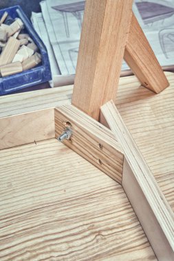 Modern marangozluk atölyesinde baş aşağı duran yeni bir kontrplak masası, kaplama ve katı ışık külünün köşesi.