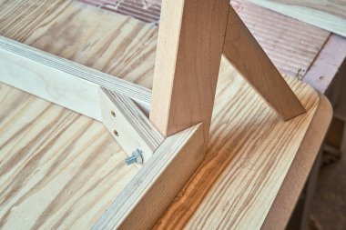 Modern marangozluk atölyesinde baş aşağı duran yeni bir kontrplak masası, kaplama ve katı ışık külünün köşesi.