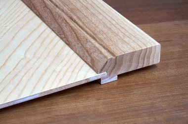 Hafif kaplamalı mobilya cephesi ve kahverengi ahşap masa üzerinde katı desenli dişbudak ahşabından yapılma yeni, şık bir detay.