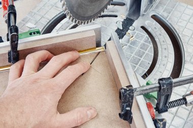 İşçi, imalat sürecinde elektrikli testereyle mobilya cephesi paneli için altın kaplama dekoratif şerit kesiyor