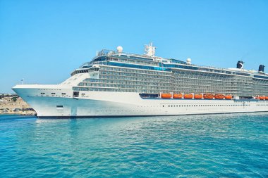 Yunanistan 'ın Rodos adası yakınlarında açık gökyüzü altında, sınırsız mavi dalgalı deniz üzerinde büyük beyaz turist yolcu gemisi
