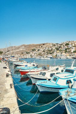 Yunanistan 'ın Suriye adasındaki güneşli bir yaz gününde, tarihi turizm şehrine karşı yansıyan demirlemiş motorlu tekneler