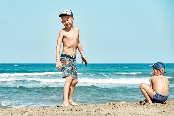 面白い楽しい弟ですショートパンツの再生オンビーチぬれた砂対紺碧の海の波と青空上の夏の日プラソニシ岬 — ストック写真