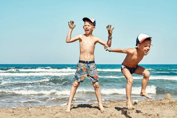 面白い喜びの弟でショートパンツビーチでジャンプします 湿った砂対紺碧の海の波と青い空夏の日にPrasonisiの岬 — ストック写真