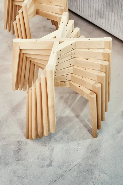 Stacks of new wooden bases with simple legs for elegant chairs assembling in light paint spraying booth at workshop closeup