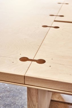 Marangozluk fabrikasının hafif atölyesinde atölye bağlantıları için delikler açan yeni büyük ahşap yemek masasının bir parçası.