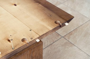 Güneşli bir günde büyük ahşap yemek masası atölye konnektörleri ve açık havada vidalar monte edilir.