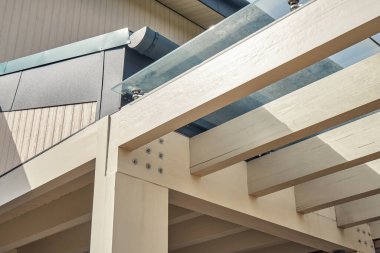 Güneşli bir günde modern yazlık evde sade ahşap kirişlerle yapılmış rahat bir pergola leşi.