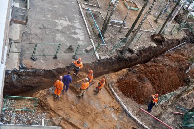 İzhevsk, Rusya - 08 Mayıs 2021: Tuğgeneralle birlikte çalışanlar, bahar günü üst görünümde konut inşaatındaki yeni su boru hattının yakınında durdular