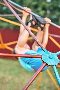 Neşeli küçük çocuk rengarenk tırmanış oyununda baş aşağı duruyor. Baharda şehir parkında yakın plan barlara ve bağlanmaya odaklanıyor.