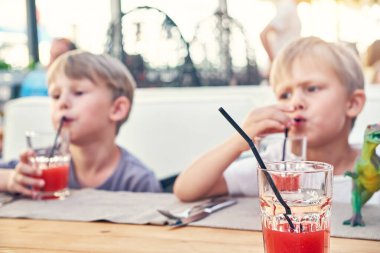 Şirin sarışın kardeşler yaz akşamları kafenin ahşap masasında oturmuş pipetle taze çilek suyu içerler.