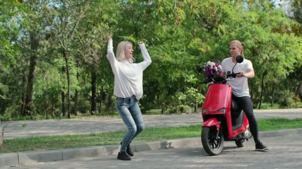 Děvče Tancuje Parku Chlap Sedí Červeném Mopedu Hodí Dívce Kytici — Stock video