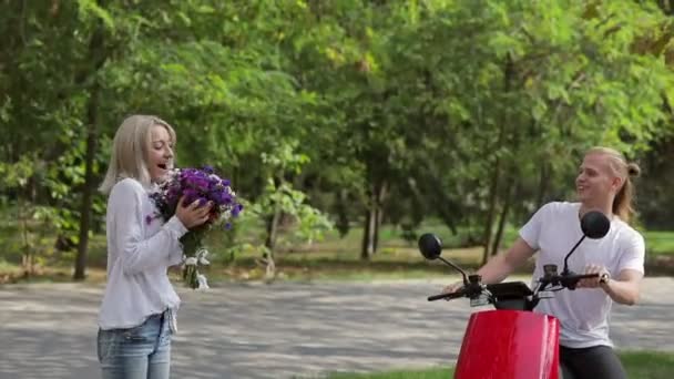 Facet Czerwonym Motorowerze Rzuca Bukiet Kwiatów Dziewczynie Parku Dziewczyna Zaczyna — Wideo stockowe
