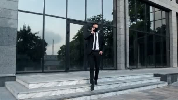 Mężczyzna Garniturze Rozmawiający Przez Telefon Wychodzi Budynku Szklanymi Oknami Swojego — Wideo stockowe