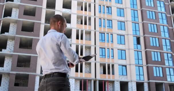 Een Man Staat Tegenover Een Huis Aanbouw Werkt Een Tablet — Stockvideo