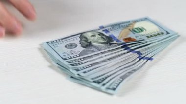 Bir adam masadan 100 dolarlık banknotları eliyle kaldırır ve yerine bir yığın bitcoin koyar..
