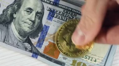 Yakın plan, altın bitcoin 100 dolarlık banknotlara yerleştiriliyor ve banknotun portresindeki gözler yerine bitcoin ortaya çıkıyor..