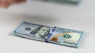 Yakından, bir adamın 100 dolarlık banknotların üzerine elini koyduğu bir bitcoin. Bitcoin 'in ağırlığına karşı dolar..