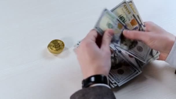 男は彼の手でお金を数え それをテーブルの上の山に折り 1ビットコインを取ります ビットコインへの金融投資 — ストック動画