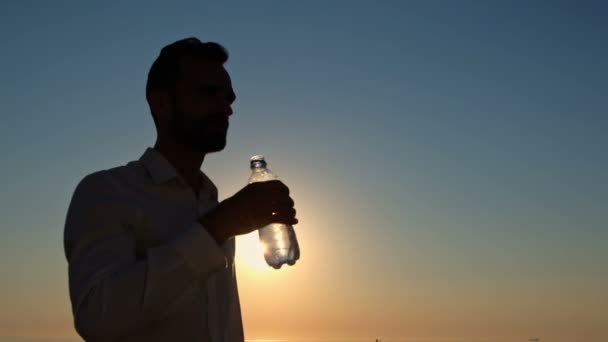 Hombre Silueta Bebe Agua Una Botella Plástico Contra Telón Fondo — Vídeos de Stock