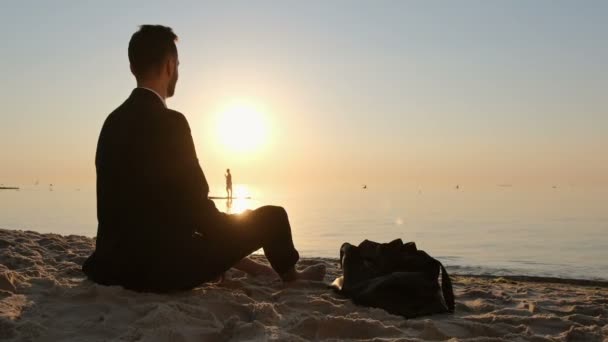 Hombre Con Traje Descansa Amanecer Sentado Orilla Del Mar Bebiendo — Vídeo de stock