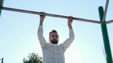 Beyaz gömlekli bir adam arka güneş ışınlarıyla turnikeye tırmanmaya başlar. İş dünyasından insanların sağlıklı ve aktif yaşam tarzları.