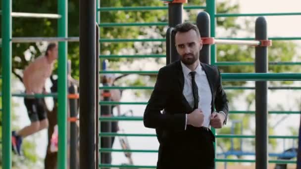 Ein Mann Businessanzug Knetet Seinen Körper Auf Dem Sportplatz Zieht — Stockvideo