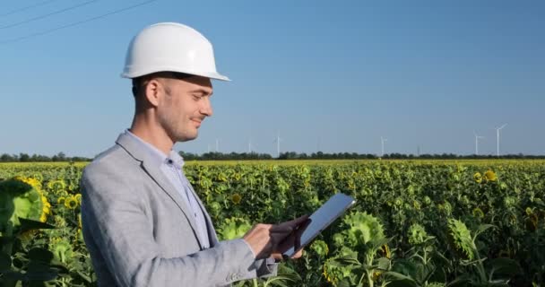 Чоловік Білому Шоломі Працює Планшеті Потім Дивиться Вітряні Млини Горизонті — стокове відео