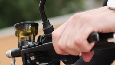 Bir adam motosikletinin direksiyonundaki tutacağa basarak frenin durumunu kontrol eder..