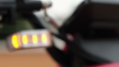 Metnin altındaki bulanık video, motosikletin direksiyonundaki farlar sarı yanıp sönüyor..