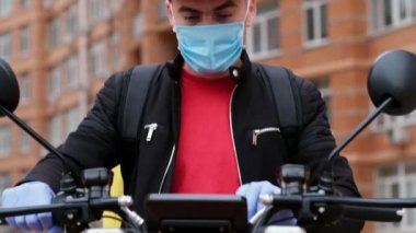 Kurye, elektrikli motosiklet direksiyonunun elektronik tabletindeki teslimat adresini kontrol eder ve video çerçevesini bırakır..