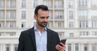 Takım elbiseli bir adam akıllı telefonuyla bir mesaj açar ve bilgiye şaşırır, gülümser ve etrafa bakar. Müjdeli bir mesaj..