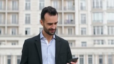Takım elbiseli bir adam akıllı telefonuyla bir mesaj açar ve bilgiye şaşırır, gülümser ve etrafa bakar. Müjdeli bir mesaj..