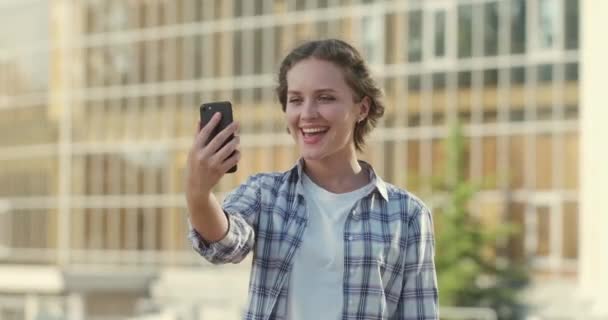Šťastná žena v kostkované košili dělá videokall na mobilu — Stock video