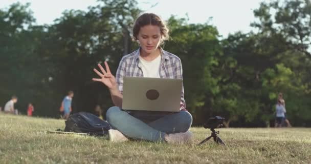 Γυναίκα μιλάει στο videocall σε φορητό υπολογιστή και smartphone στο πάρκο — Αρχείο Βίντεο