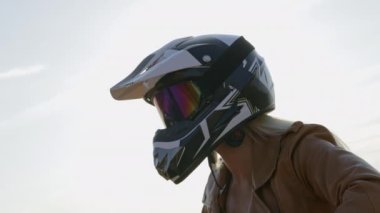 Kask takan kadın motosiklet freni gidonuna basıyor.