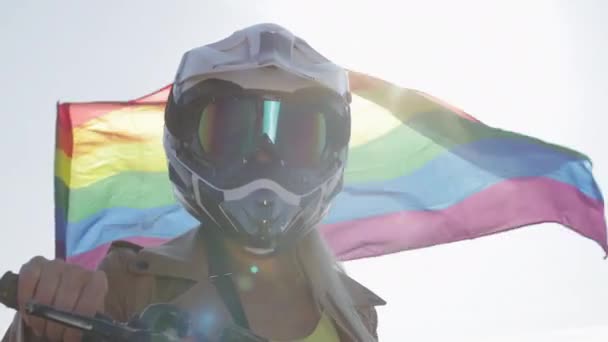 Blonde Frau in Lederjacke und Helm bei Regenbogenfahne — Stockvideo