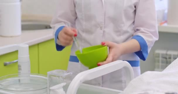 Esthéticienne mélange des produits cosmétiques dans un bol vert au bureau — Video
