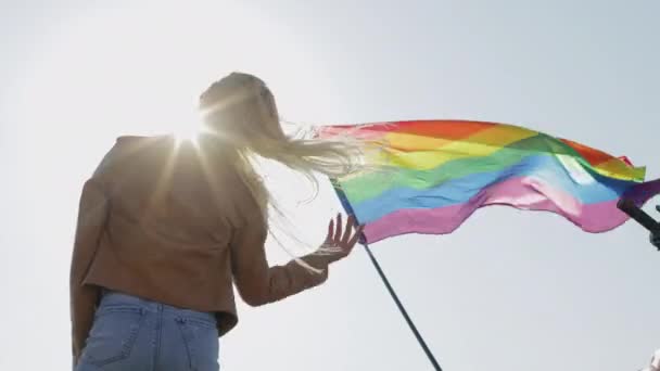 Блондинка в шоломі піднімає руки в повітря біля прапора — стокове відео