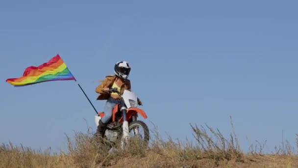 Mulher em moto esportiva com passeios de bandeira no campo de grama seca — Vídeo de Stock