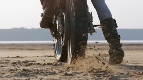 Гонщик начинает мотоцикл на песке, создавая куски грязи — стоковое видео