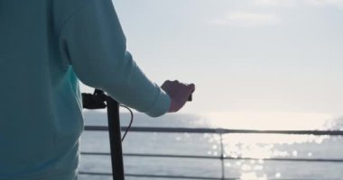 Elektrikli scooterlı adam, metal korkuluklara denizden yaklaşıyor.