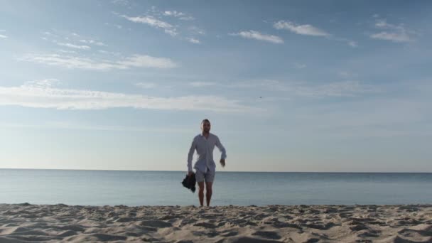 Entzückter Geschäftsmann in Anzug und Shorts springt am Strand — Stockvideo